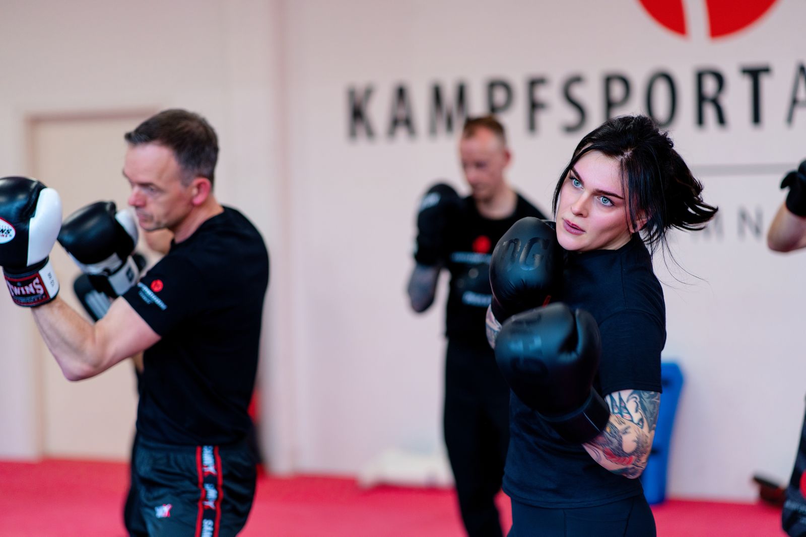 Kickbox-Training: Trainer und Teilnehmerin in Deckung vor dem Schriftzug der Akademie