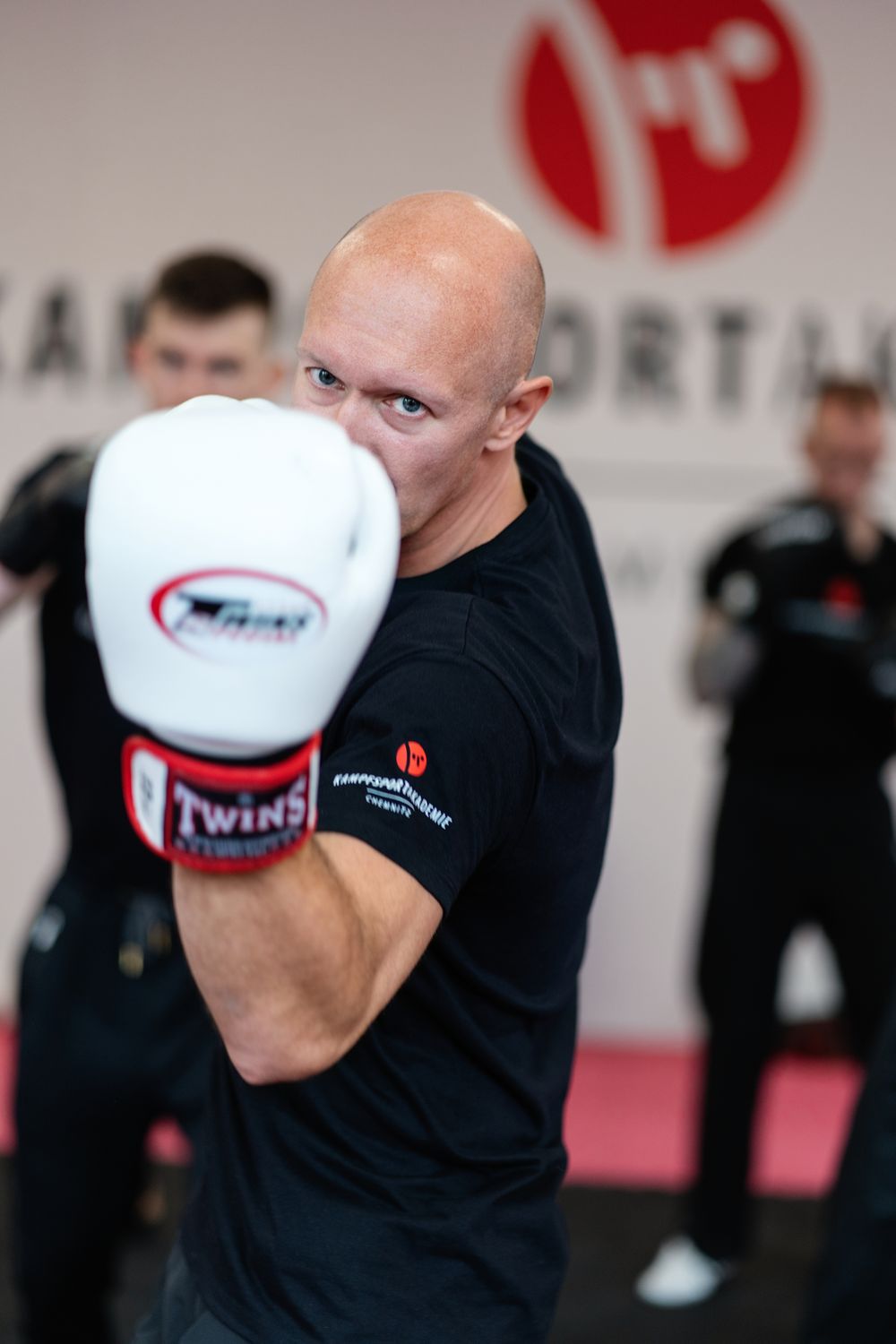 Torsten Fischer schlägt mit Boxhandschuh in Richtung Kamera, dahinter trainiert die Gruppe