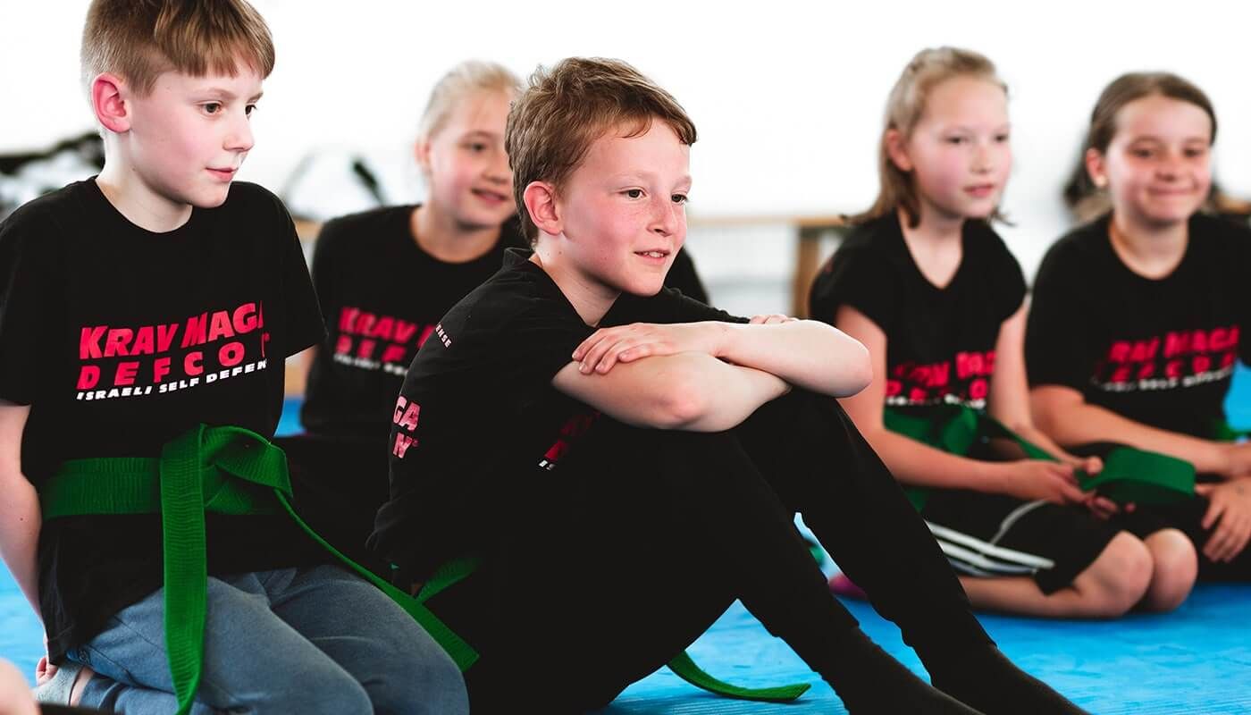 Kinder sitzen im Training zusammen und hören zu