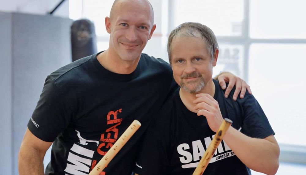 Zwei Trainer der Akademie Arm in Arm mit Trainingsstöcken